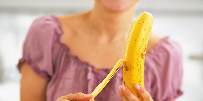 Closeup on young woman peeling banana