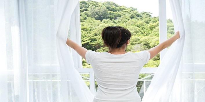 Asian young woman opening the curtains to a new day.