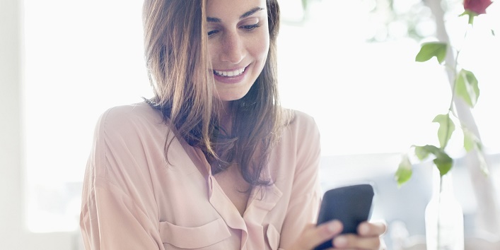 Smiling businesswoman checking cell phone