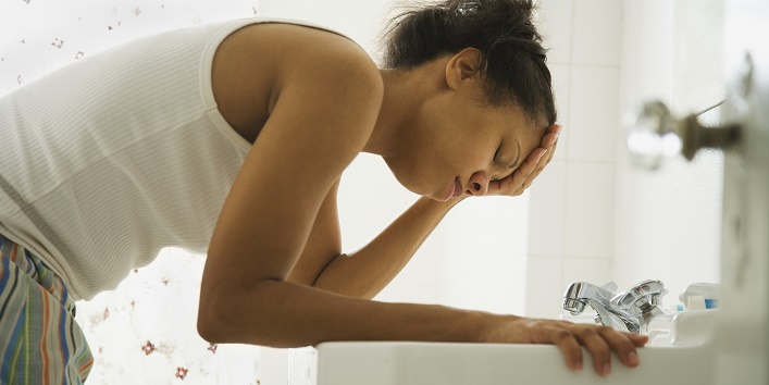 African woman leaning over bathroom sink with head in hand