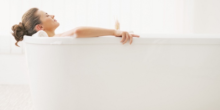 relaxed young woman laying in bathtub