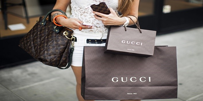 A pedestrian carries Gucci-branded shopping bags and a Louis Vuitton SA handbag as she walks along the Rue du Rhone in Geneva, Switzerland, on Saturday, June 9, 2012. Swiss economic growth unexpectedly accelerated in the first quarter, led by consumer demand. Photographer: Valentin Flauraud/Bloomberg via Getty Images
